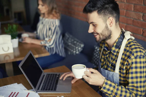 Barman trabalhando enquanto toma uma xícara de café — Fotografia de Stock