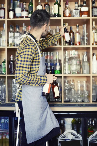 Bartender against alcohol shelfs — Stock Photo, Image