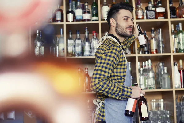 Bartender next to shelf with alcohol — Stock Photo, Image