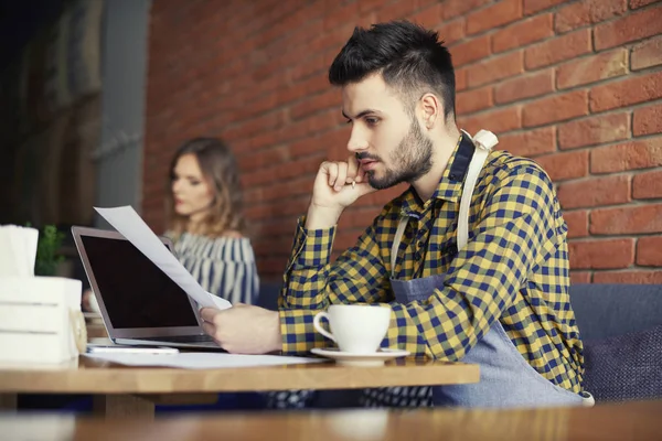 Nachdenklicher Mann mit der Hand am Kinn über Papierkram — Stockfoto