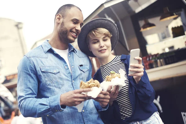 Casal usando telefone celular enquanto tem fast food — Fotografia de Stock