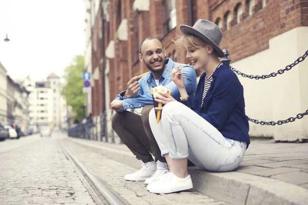 Pareja teniendo comida rápida sentado en la acera — Foto de Stock