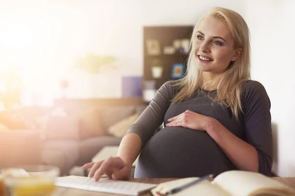 Беременная женщина печатает на клавиатуре — стоковое фото