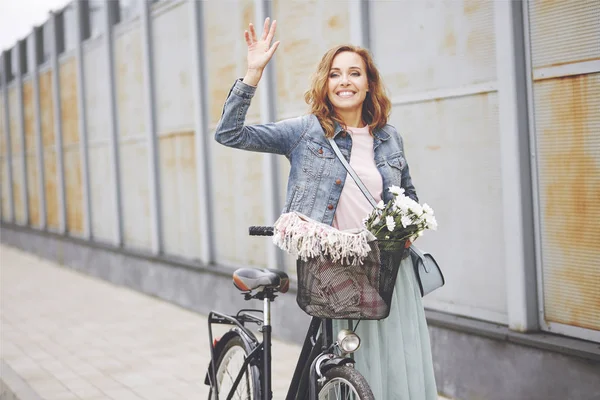 Женщина с велосипедом машет — стоковое фото