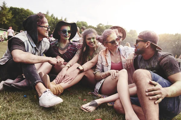 Vänner som sitter på gräset på musikfestival — Stockfoto