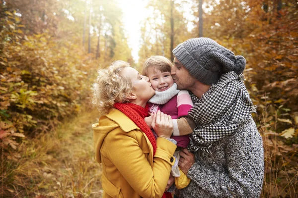 Joyful scene of parents kissing daughter — Stock Photo, Image