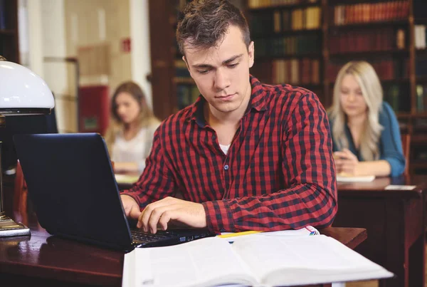 Estudante do sexo masculino estudando na biblioteca — Fotografia de Stock