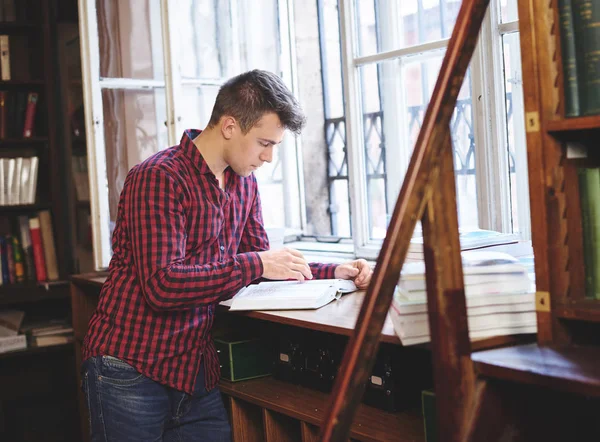 Studente maschio che studia in biblioteca — Foto Stock