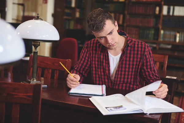 Mannelijke student studeert aan de bibliotheek — Stockfoto