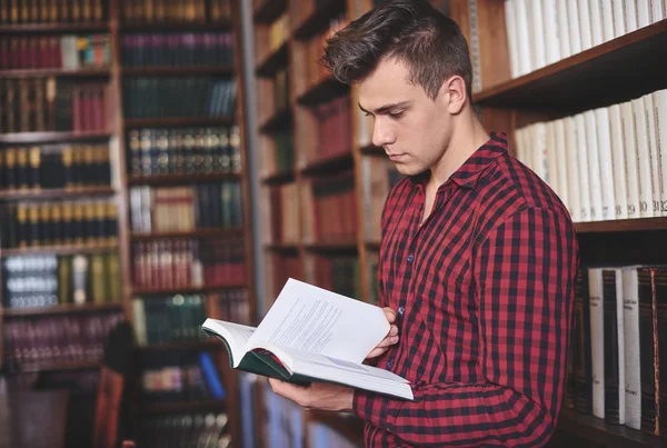 Hombre hojeando un libro en la biblioteca — Foto de Stock