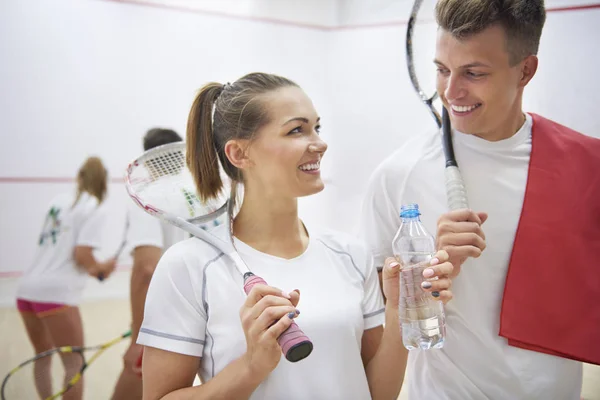 man and woman holding squash rackets