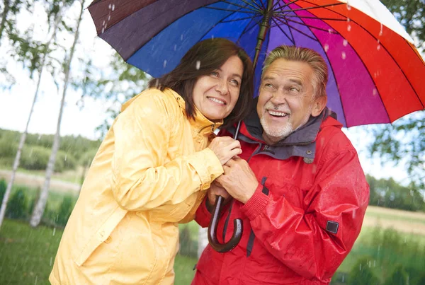 Casal adulto compartilhando um guarda-chuva — Fotografia de Stock