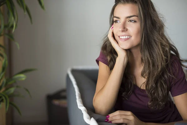 Mujer sentada en el sofá y sonriendo — Foto de Stock