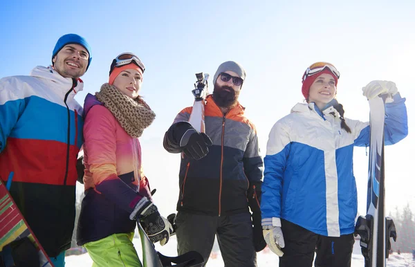 Glada kompisar med snowboards och skidor — Stockfoto