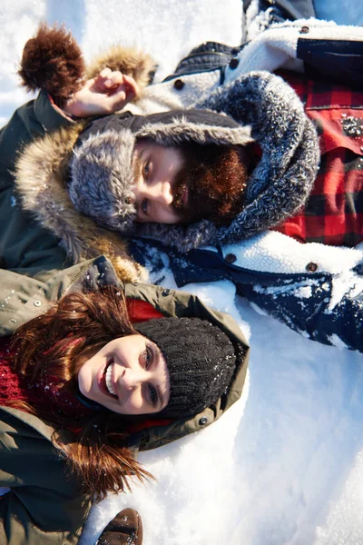 Casal deitado na neve branca — Fotografia de Stock