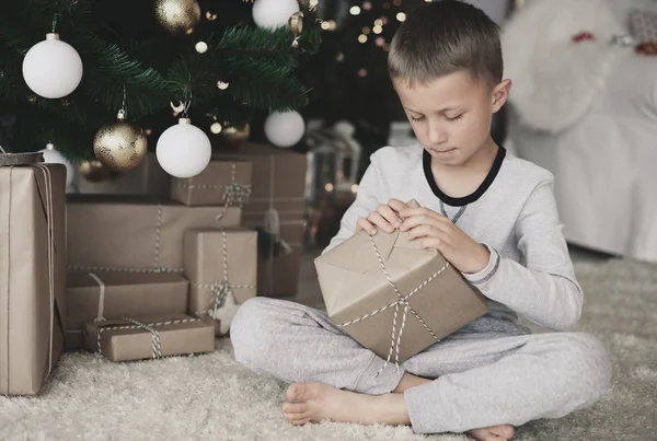 Chico en pijama abriendo un regalo — Foto de Stock