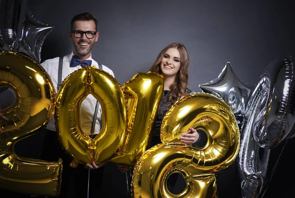 Pareja alegre sosteniendo globos de año nuevo —  Fotos de Stock