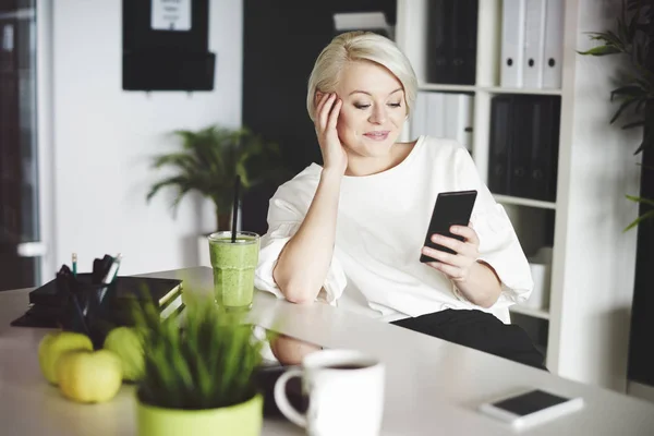 Žena sledujete vtipné video na mobilním telefonu během přestávky — Stock fotografie