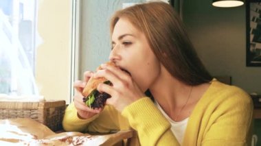 Kadın pencerede bir sandviç yemek 