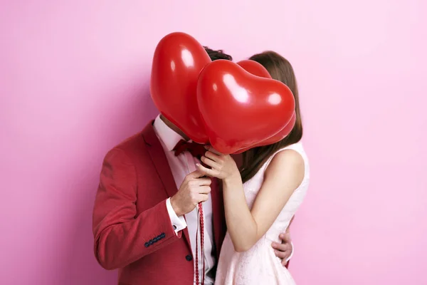 Casal beijando atrás do balão — Fotografia de Stock