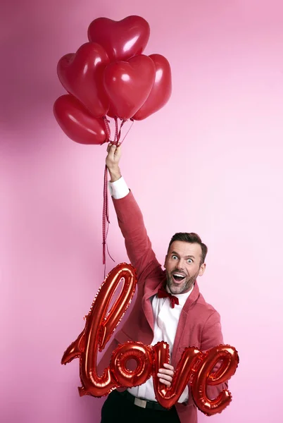 Funny man holding bunch of balloons heart shape — Stock Photo, Image