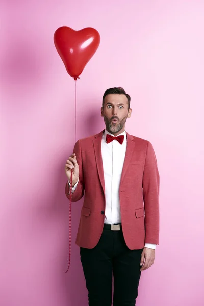Překvapený muž drží balónek tvaru srdce — Stock fotografie