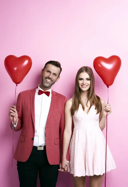 Aanhankelijk paar met hart vorm ballonnen hand in hand — Stockfoto