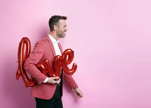 Cheerful man helping to preparing decorations for valentine's party — Stock Photo, Image
