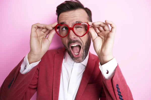 Hombre alegre probando gafas en forma de corazón — Foto de Stock