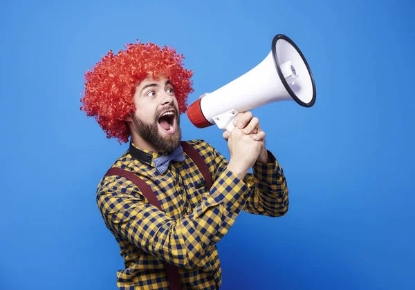 Cara alegre com peruca gritando em megafone — Fotografia de Stock