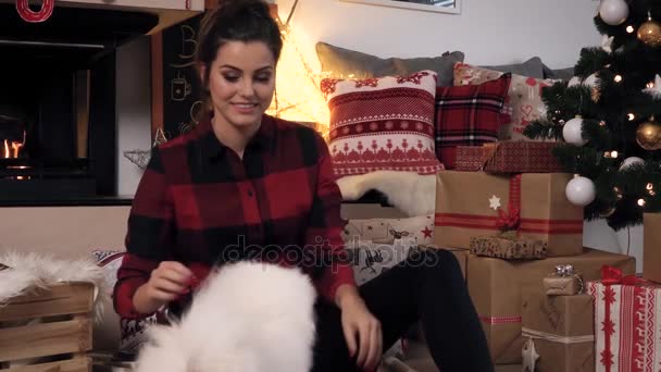 Mulher abraçando seu cão pequeno bonito no Natal — Vídeo de Stock