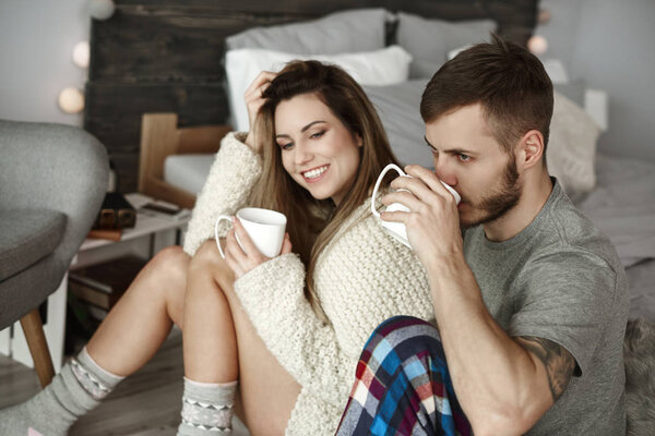 Affectionate couple drinking morning coffee at bedroom 