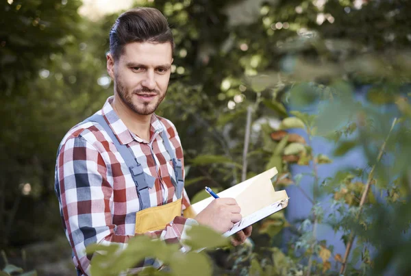 Uomo Prende Appunti Negli Appunti Mentre Controlla Fiori — Foto Stock