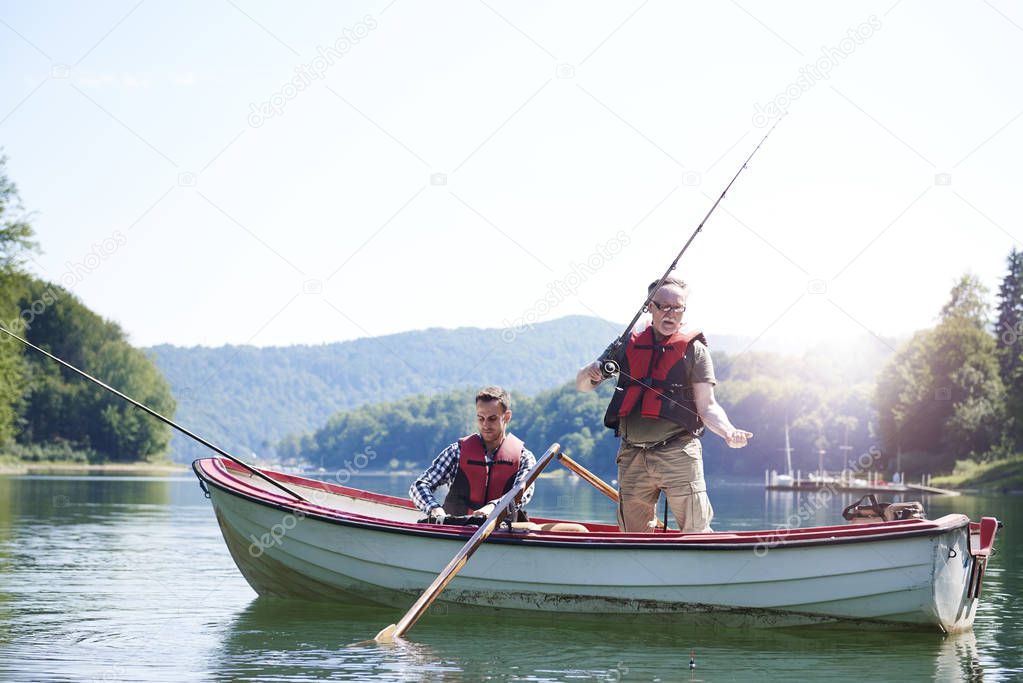 Senior man with son fishing in lake 
