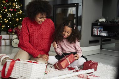 Afrikalı kadın ve kızı Noel hediyelerini paketliyor.