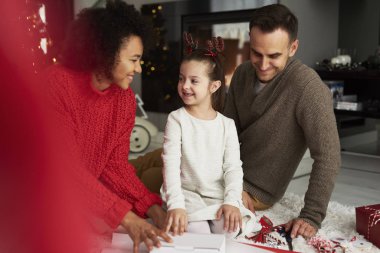 Family packing Christmas presents in living room  