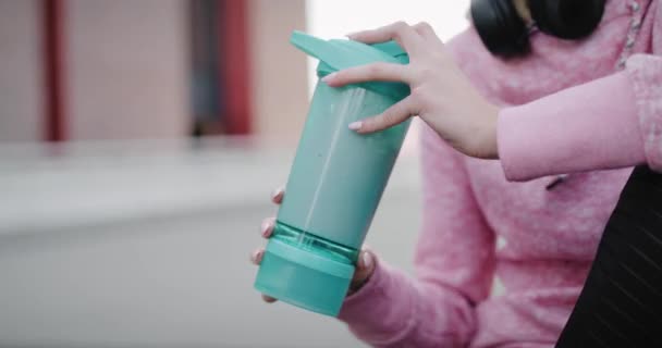 トレーニング後にタンパク質飲料を飲む女性のハンドヘルドビュー — ストック動画