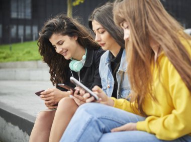Akıllı telefonlarını kullanan üç kızın yan görüntüsü 