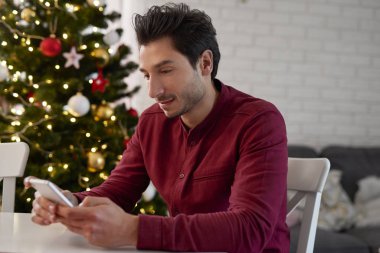 Cep telefonlu bir adam Noel için en iyi dileklerini gönderiyor.