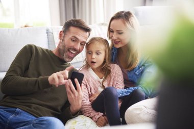Oturma odasında cep telefonu olan bir aile 