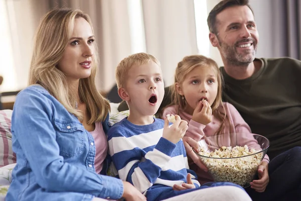 İki çocuklu bir aile oturma odasında televizyon izliyor. 