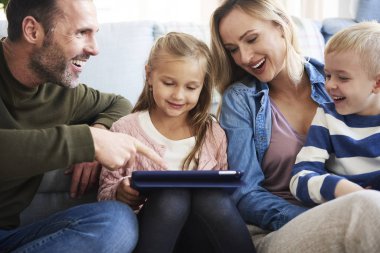 Oturma odasında tablet kullanan neşeli bir aile 