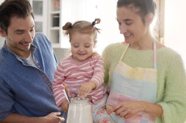 Ebeveynler ve kızları birlikte yemek pişiriyorlar.