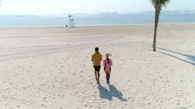 Drone view of woman running with partner. Shot with RED helium camera in 8K