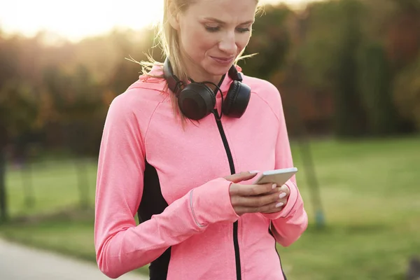 Samica Sportowca Korzystająca Telefonu Komórkowego Podczas Treningu Joggingowego — Zdjęcie stockowe