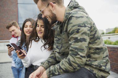 Group of young people using mobile phone on fresh air