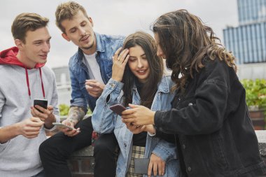 Group of friends using their mobile phone in the city 