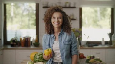 Mutfakta biber tutan güzel bir kadın.