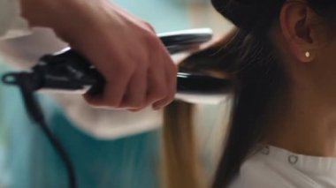 Saç düzleştirici ve tarak kullanan bir kuaförün el kamerası görüntüsü. 8K 'da kırmızı helyum kamerayla çekildi.