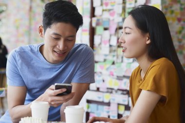 Adam kız arkadaşıyla buluşurken cep telefonu kullanıyor.